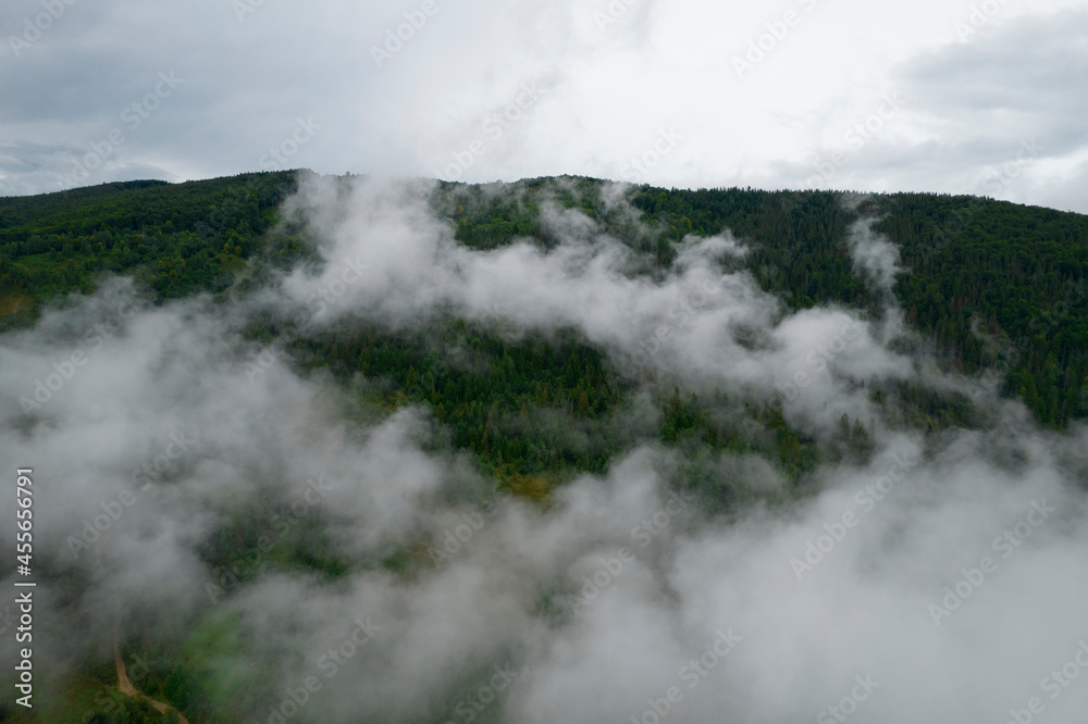 Flying over the clouds during morning sunrise in Carpathian Mountains. Above.Golden fluffy clouds moving softly on the sky and the sun shining through the clouds with beautiful rays and lens flare.