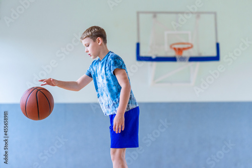 School kid playing basketball in a physical education lesson. Horizontal education poster, greeting cards, headers, website. Safe back to school during pandemic concept © Augustas Cetkauskas