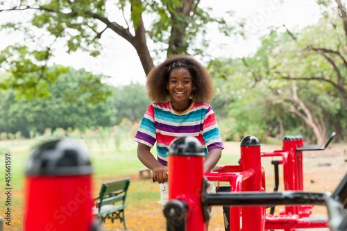 Cute African American girl with curly hair playing at the playground in the park. © amorn
