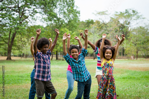 Foto Group of African American children playing and raising their hands in the park