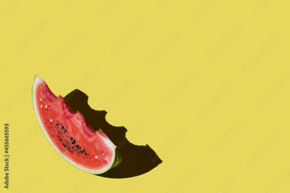 Obraz premium a piece of bitten watermelon on a yellow background