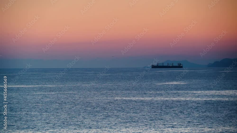 Evening seascape with cargo container industrial ship anchored waiting for entering Carboneras port in Almeria, Spain. Mediterranean sea coast. Logistic shipping concept. Evening seascape with cargo container industrial ship anchored waiting for entering Carboneras port in Almeria, Spain. Mediterranean sea coast. Logistic shipping concept.