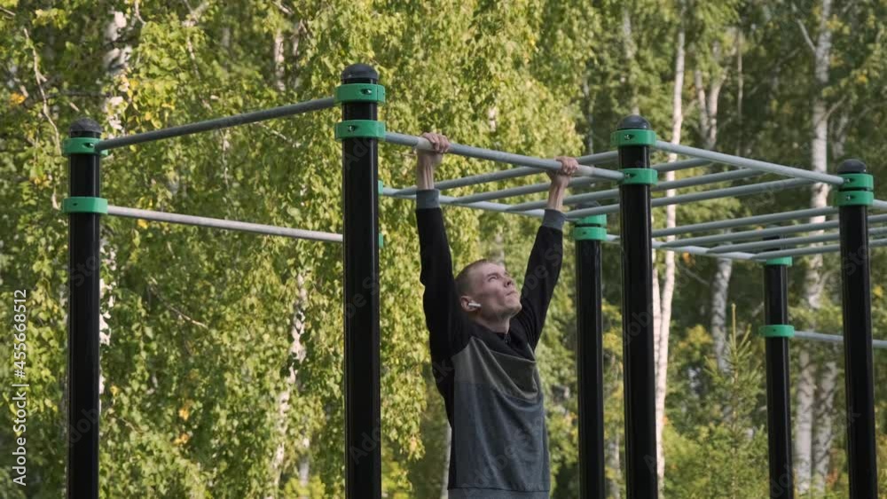 Young Man Doing Pull-ups on a Horizontal Bar Outdoors. Sport, Fitness, Street Workout and Healthy Lifestyle Concept Young Man Doing Pull-ups on a Horizontal Bar Outdoors. Sport, Fitness, Street Workout and Healthy Lifestyle Concept