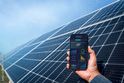Bild auf Leinwand Man hand holding the telephone for monitoring performance in solar power plant(solar cell)