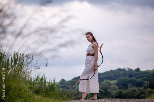 A Hungarian woman in a linen dress with a bow is standing on the road