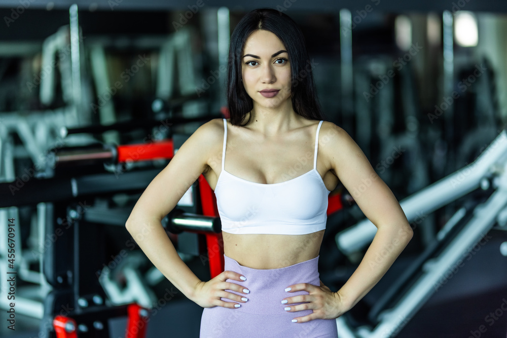 Full length shot of young woman in sportswear taking a walk in the cross fit gym. Fitness female getting ready for intense crossfit workout. Full length shot of young woman in sportswear taking a walk in the cross fit gym. Fitness female getting ready for intense crossfit workout.