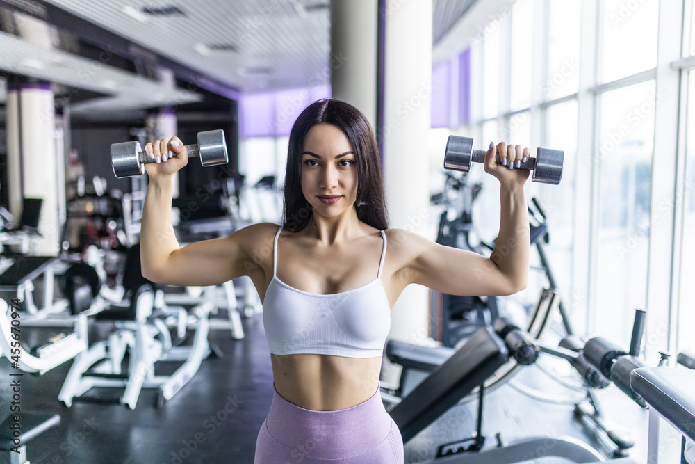 Yang pretty woman works out with dumbbels in gym. Yang pretty woman works out with dumbbels in gym.