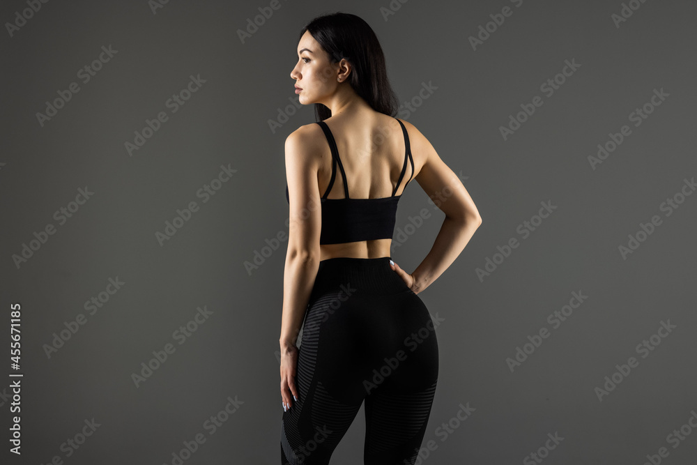Portrait of sporty woman with muscular body, posing against a gray background Portrait of sporty woman with muscular body, posing against a gray background