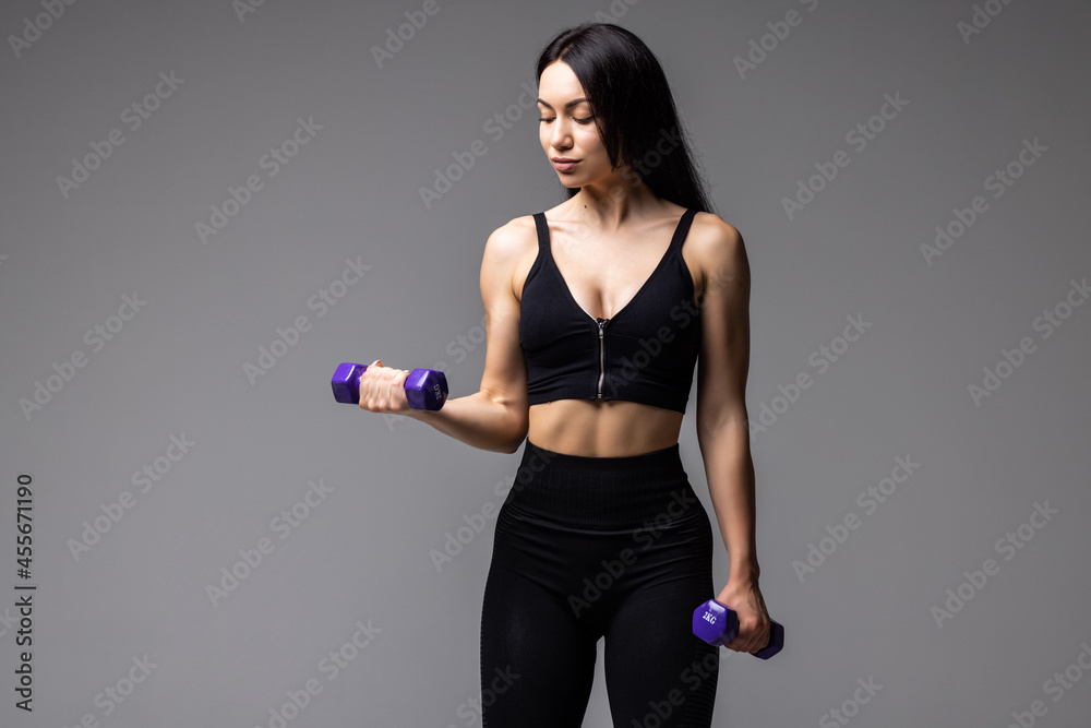Young fit woman lifting dumbell on gray Background Young fit woman lifting dumbell on gray Background