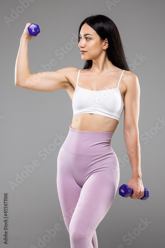 Young attractive happy latin woman in sport clothes with beautiful smile holding weight dumbbell doing fitness workout isolated on white background
