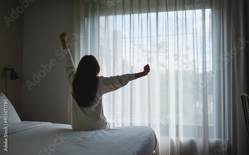 Fototapeta Naklejka Na Ścianę i Meble -  Rear view image of a woman do stretching after waking up in bedroom