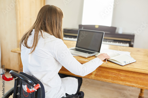 Woman in a wheelchair with paraplegia works on the laptop photo