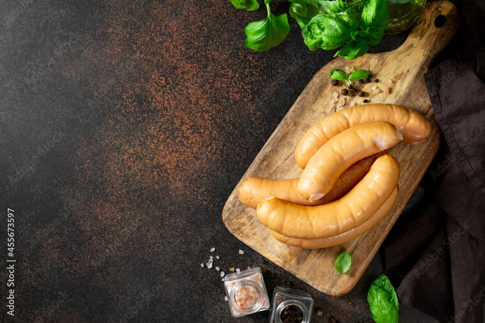 Pork sausages on a serving wooden board on a dark culinary background top view with copyspace