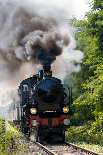 Vintage steam train runs on the tracks in the countryside