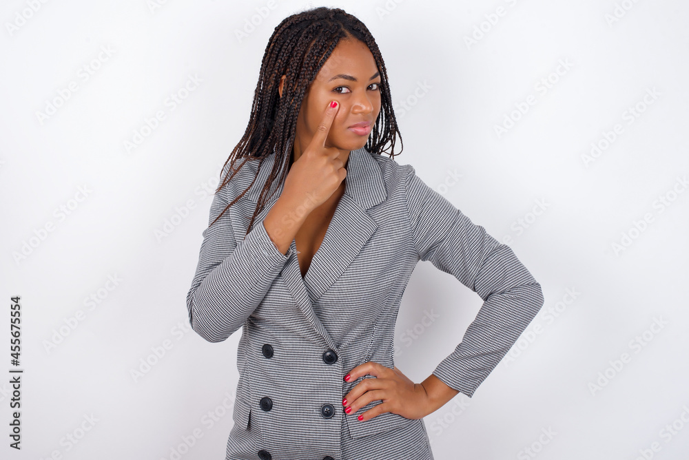 Young african american business woman with braids over white wall, looking, observing, keeping an eye on an object in front, or watching out for something. Young african american business woman with braids over white wall, looking, observing, keeping an eye on an object in front, or watching out for something.