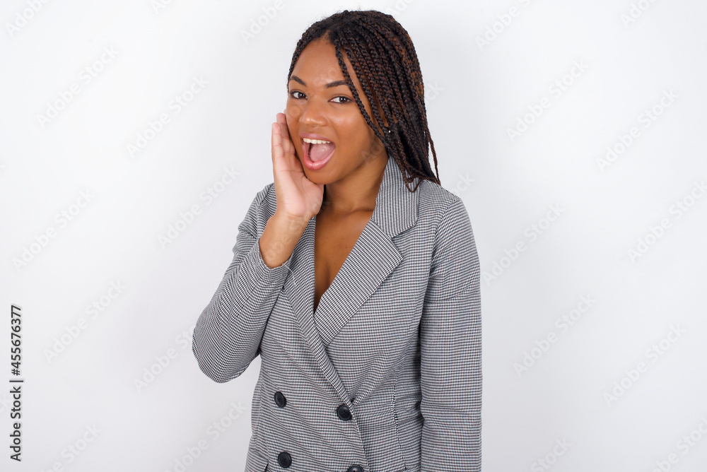 Shocked, astonished Young african american business woman with braids over wh looking surprised in full disbelief wide open mouth with hand near face. Positive emotion facial expression body language. Shocked, astonished Young african american business woman with braids over wh looking surprised in full disbelief wide open mouth with hand near face. Positive emotion facial expression body language.