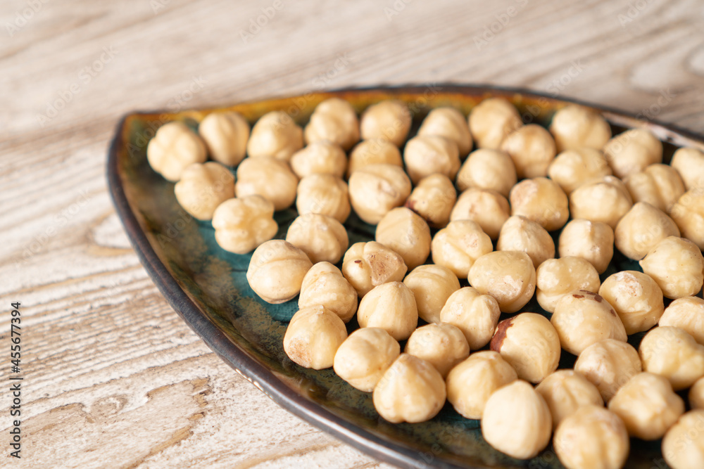 Hazelnuts in selective focus. Nuts on a plate on a white background. Dry hazelnuts. Roasted hazelnuts on a wooden table Hazelnuts in selective focus. Nuts on a plate on a white background. Dry hazelnuts. Roasted hazelnuts on a wooden table