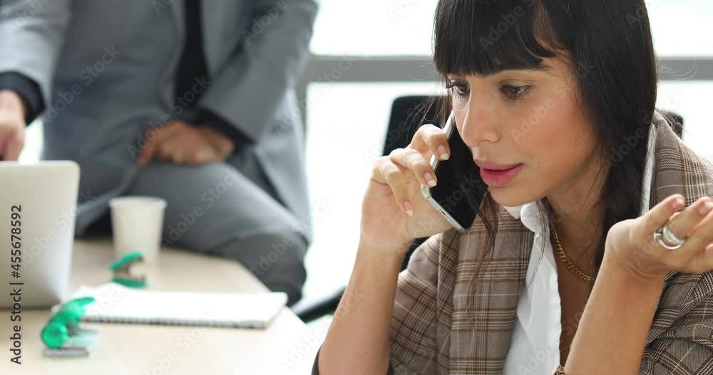 Happy young business woman talking and using mobile phone while working at home with laptop Happy young business woman talking and using mobile phone while working at home with laptop