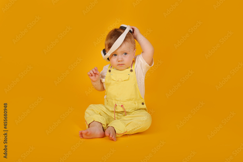 a beautiful blue-eyed little boy in a yellow suit is sitting in white headphones a beautiful blue-eyed little boy in a yellow suit is sitting in white headphones