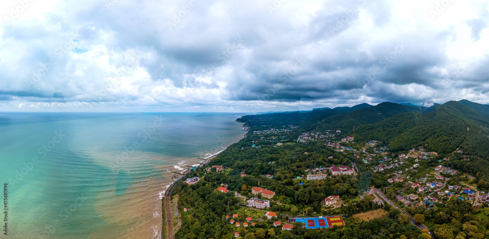 aerial landscape of the sea coast near forested mountains on a rainy summer day. The sea water is muddy and dirty due to rain streams flowing down from the mountains