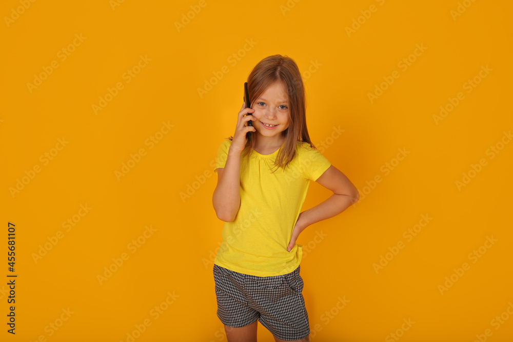 a beautiful brown-haired girl in a yellow T-shirt is talking on the phone yellow background a beautiful brown-haired girl in a yellow T-shirt is talking on the phone yellow background