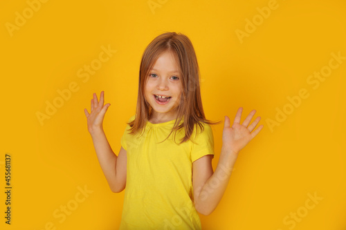 Photography a beautiful brown-haired girl in a yellow T-shirt is surprised by a yellow backg