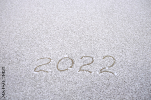 Number 2022 are written in the snow on white background, copy space