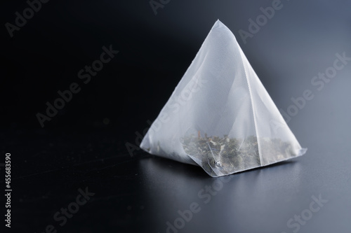 Pyramid tea bag with green tea on a dark polished gradient surface. Macro. Free space for an inscription. photo