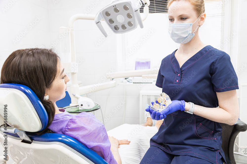 Dentistry concept. Professional dental services and modern equipment without pain. The doctor consults and treats the young woman, conducts an examination and draws up a treatment plan Dentistry concept. Professional dental services and modern equipment without pain. The doctor consults and treats the young woman, conducts an examination and draws up a treatment plan