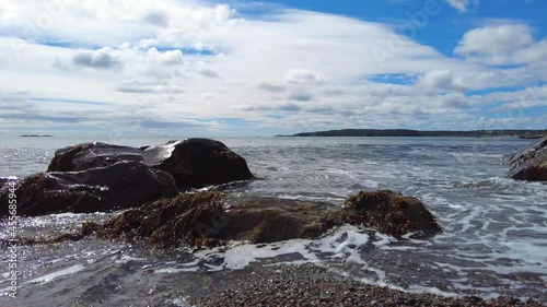 Pan shot of tide flowing over low rocks 