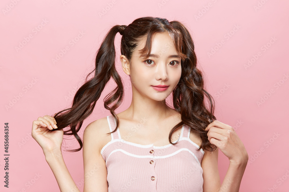 ツインテールをした若い女性のピンク背景のポートレート ツインテールをした若い女性のピンク背景のポートレート