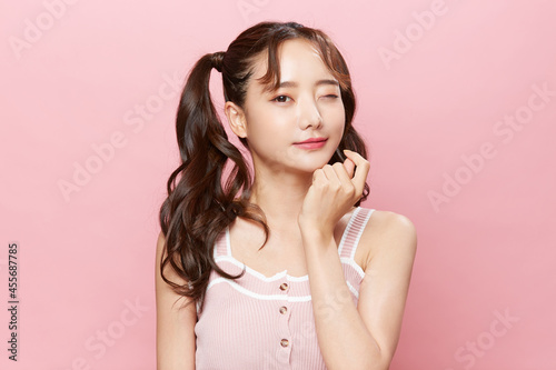 ツインテールをした若い女性のピンク背景のポートレート