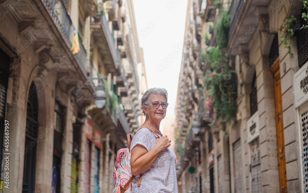 Senior smiling woman travels to Barcelona visiting the old city part enjoying the holidays