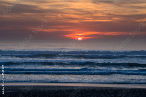 untergehende Sonne in rotem Licht mit blauem Wellen am Meer
