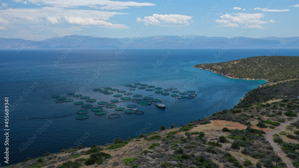 Aerial drone photo of large fish farming - breeding unit of sea bass and sea bream in huge round cages with latest technology automatic feeding system, calm deep sea of Anemokambi, Galaxidi, Greece