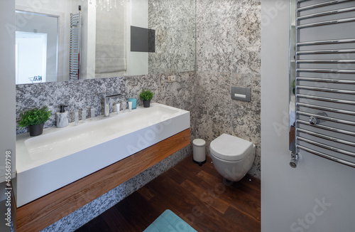 Modern bathroom granite  wooden interior. White sink  toilet.