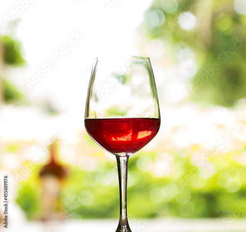 A glass of red wine is placed on a natural background wooden floor.