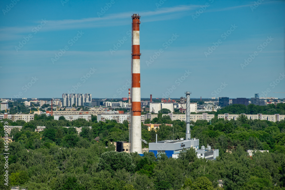 Summer cityscape. Industrial area of city. White and red factory pipe