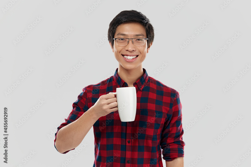 Smiling asian man holding cup with coffee or tea Smiling asian man holding cup with coffee or tea