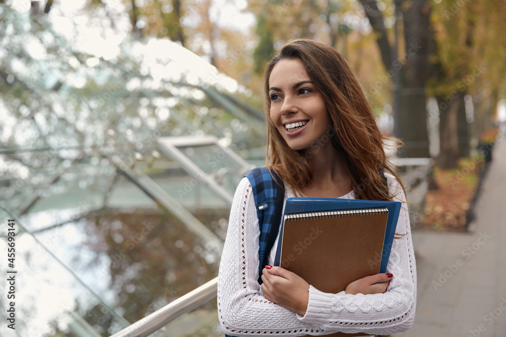 Fototapeta premium Female student with notebook and folder in city