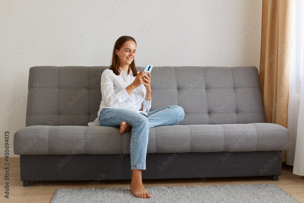 Portrait of young adult attractive woman holding mobile phone, checking social networks, looking at smart phone screen with pleasant smile, browsing internet or typing message. Portrait of young adult attractive woman holding mobile phone, checking social networks, looking at smart phone screen with pleasant smile, browsing internet or typing message.