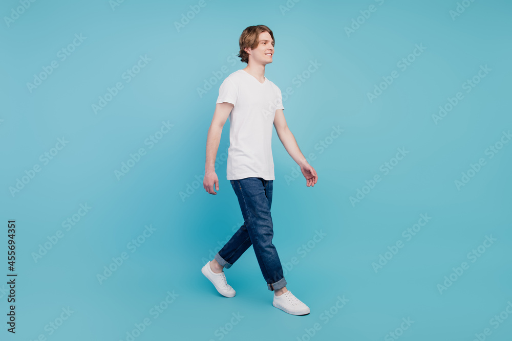 Full body photo of cheerful positive guy go copyspace isolated over blue background Full body photo of cheerful positive guy go copyspace isolated over blue background