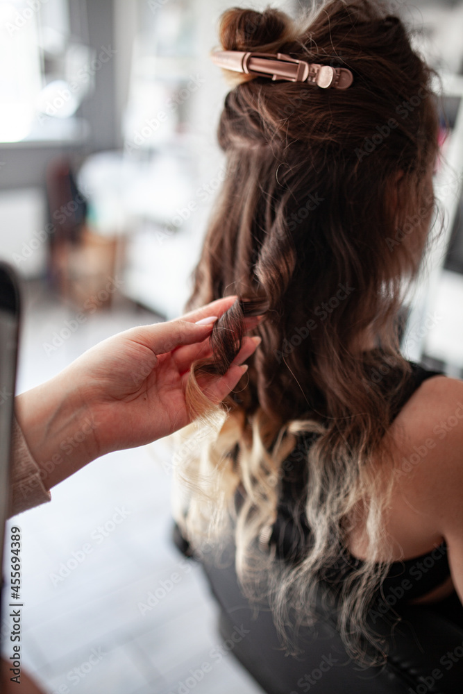 Fototapeta premium stylist hairdresser makes a hairstyle for a girl in his beauty salon, hollywood wave, beautiful hairstyle, hairdresser at work
