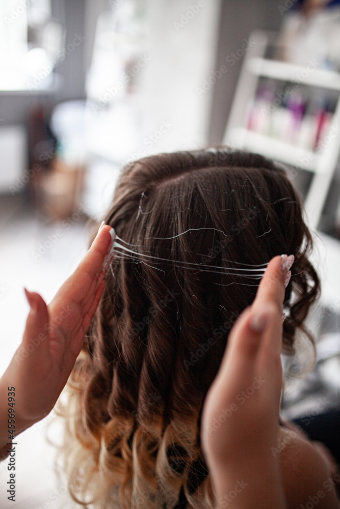 Naklejka premium stylist hairdresser makes a hairstyle for a girl in his beauty salon, hollywood wave, beautiful hairstyle, hairdresser at work