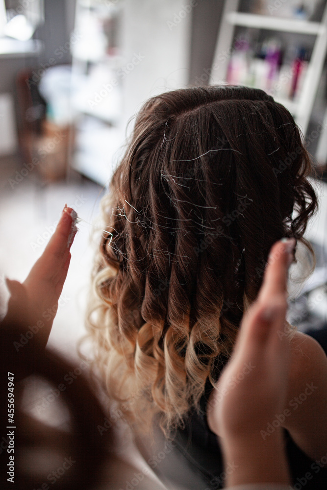 Naklejka premium stylist hairdresser makes a hairstyle for a girl in his beauty salon, hollywood wave, beautiful hairstyle, hairdresser at work