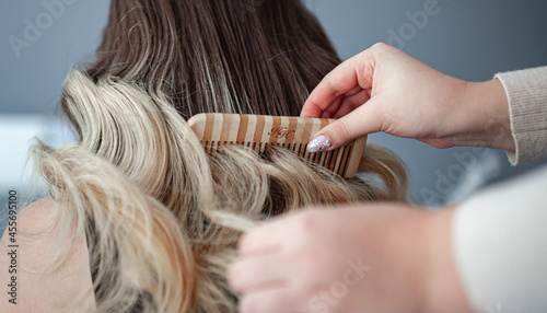 stylist hairdresser makes a hairstyle for a girl in his beauty salon, hollywood wave, beautiful hairstyle, hairdresser at work