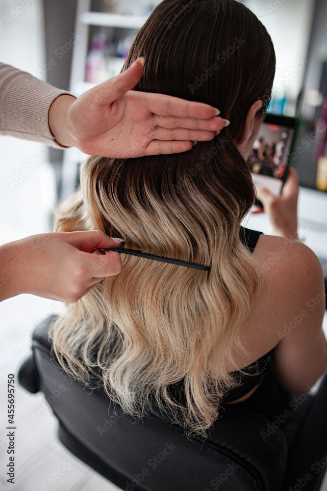 stylist hairdresser makes a hairstyle for a girl in his beauty salon, hollywood wave, beautiful hairstyle, hairdresser at work