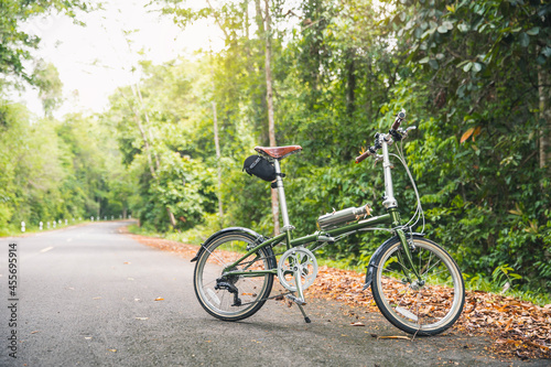 Green bicycle on the road. a green bicycle that someone parked in the forest. The bicycle concept of a healthy lifestyle and outdoor activities.