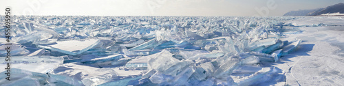A panoramic view of the endless field of ice hummocks. Pieces of blue transparent ice on the frozen Lake Baikal on a frosty winter day. Natural cold background. Unusual winter landscape