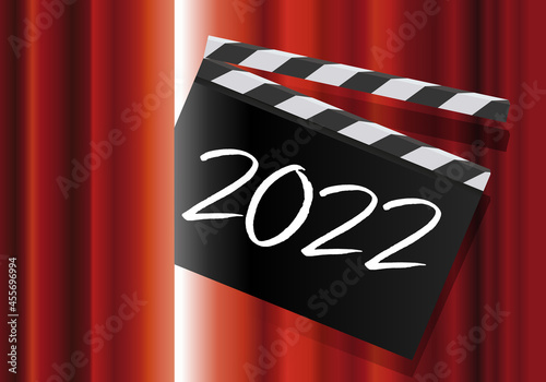 Pour présenter la nouvelle année, un clap de cinéma avec l’inscription 2022, passe au travers du rideau rouge d’une scène de spectacle.